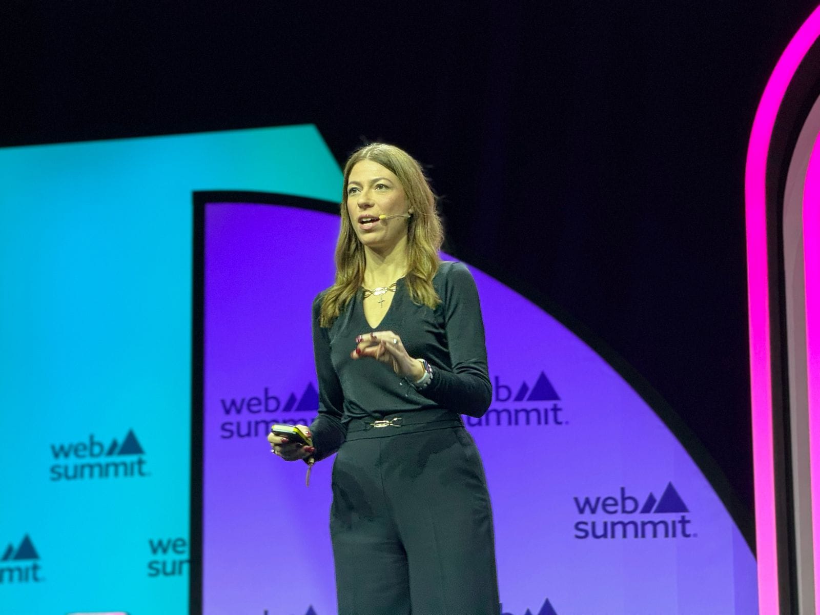 Daniela Braga no palco da Web Summit 2023 com um comando na mão direita.