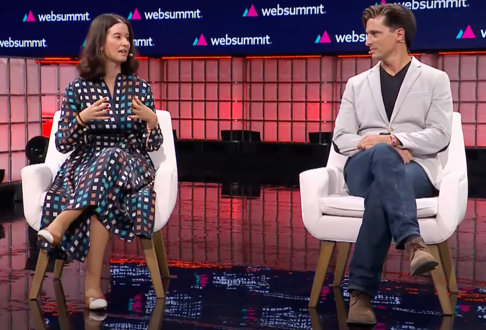 Cristina Fonseca (à esquerda) e Vasco Pedro (à direita) no palco da Web Summit 2023 sentados em cadeiras. Cristina está a gesticular enquanto fala.