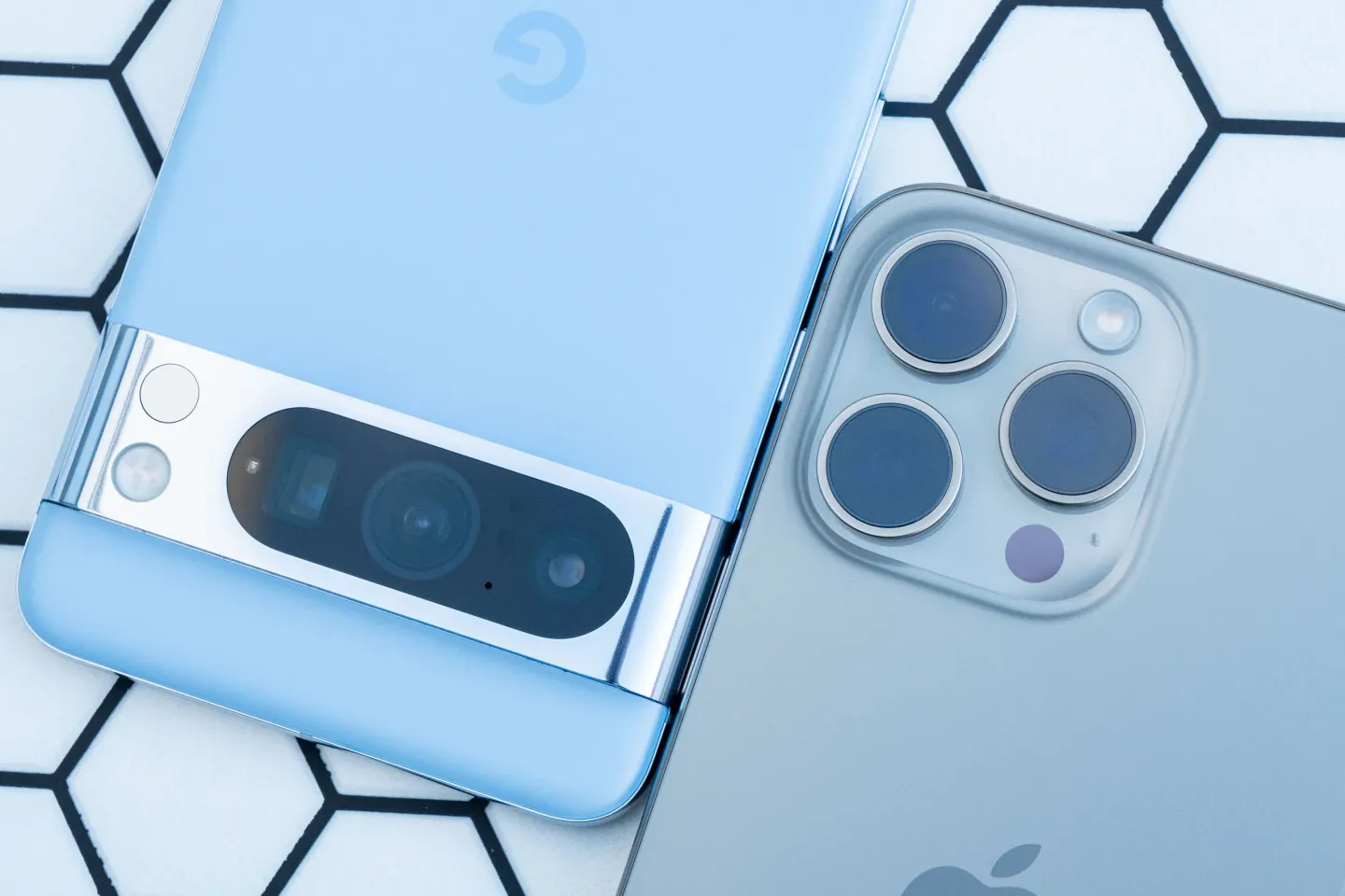 Mão esquerda a segurar um iPhone 15 Pro Max e um Google Pixel 8 Pro.